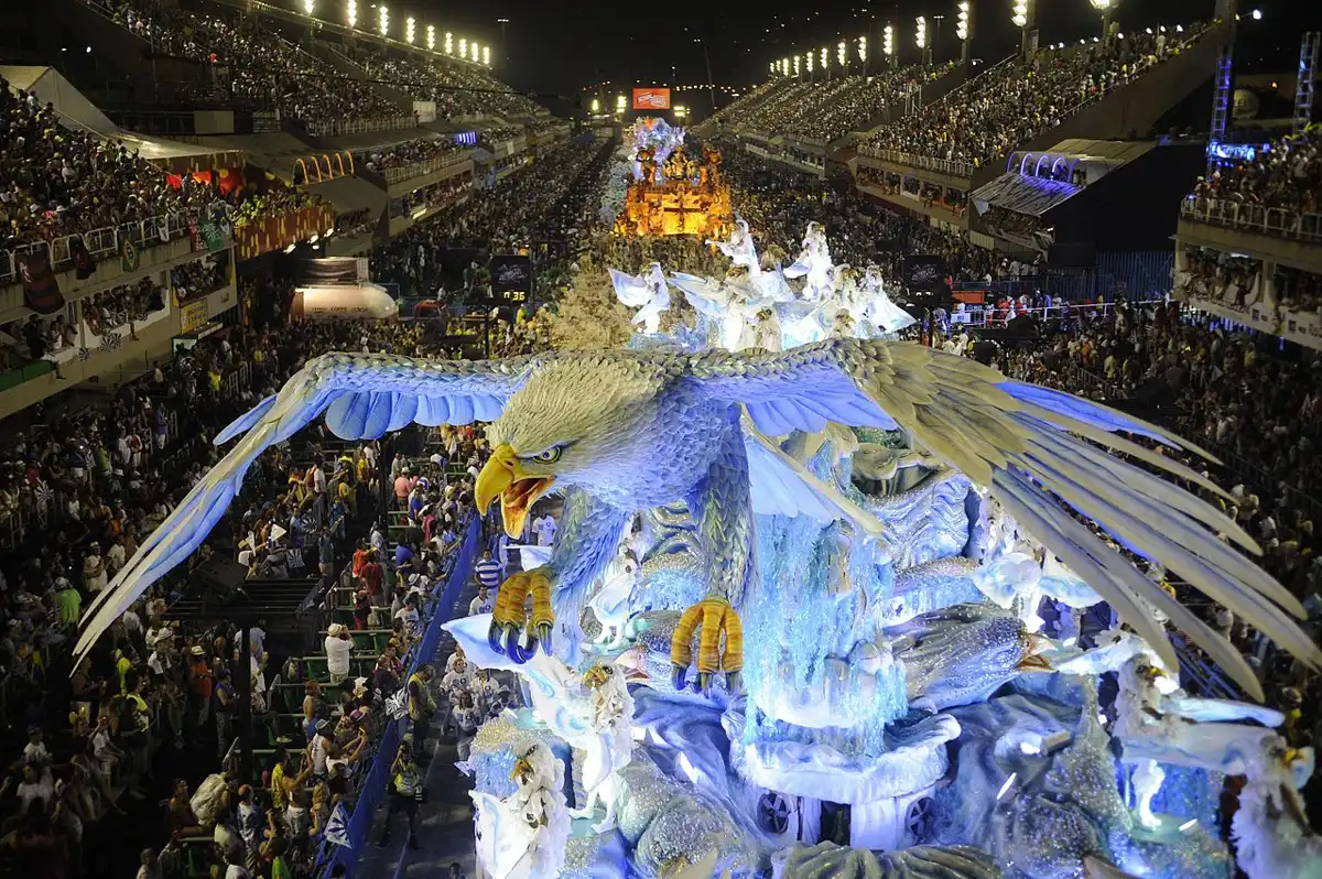 Desfile de carnaval com grande alegoria de águia e foliões ao fundo, destacando a energia e a cor do Carnaval brasileiro.