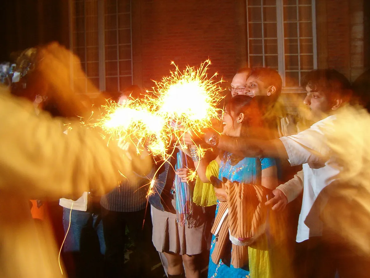 Grupo de pessoas celebrando o Diwali com fogos de artifício, sorrindo e compartilhando a alegria do festival das luzes