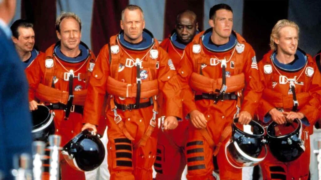 Equipe de astronautas de "Armageddon" caminhando em traje espacial antes da missão.