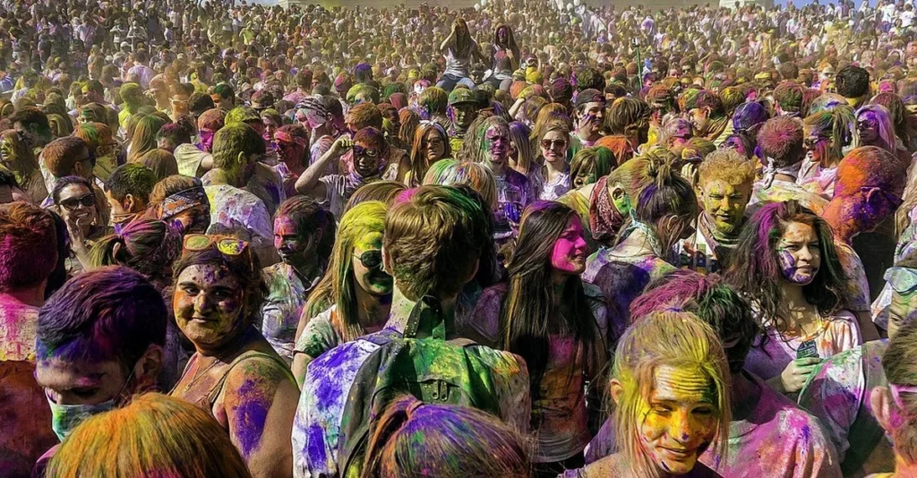 Participantes do festival Holi cobertos com pó colorido durante uma celebração alegre