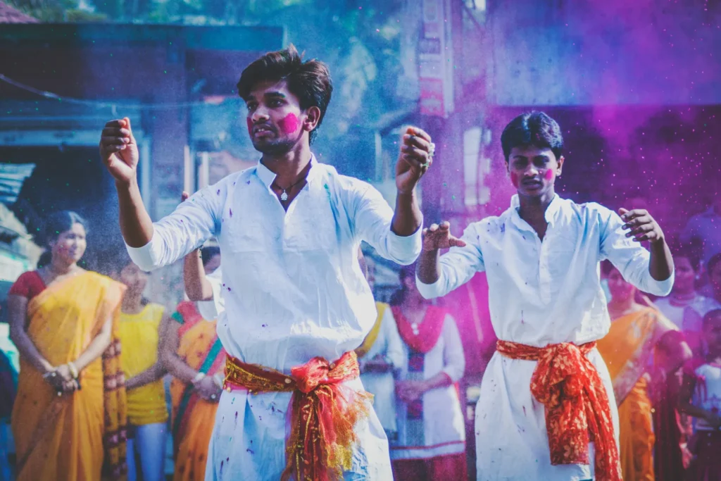 Pessoas celebrando um festival cultural com roupas tradicionais e cores vibrantes.