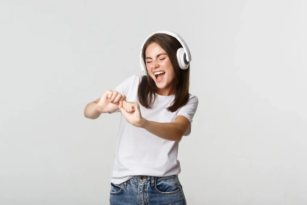 Jovem sorrindo e dançando enquanto ouve música com fones de ouvido.