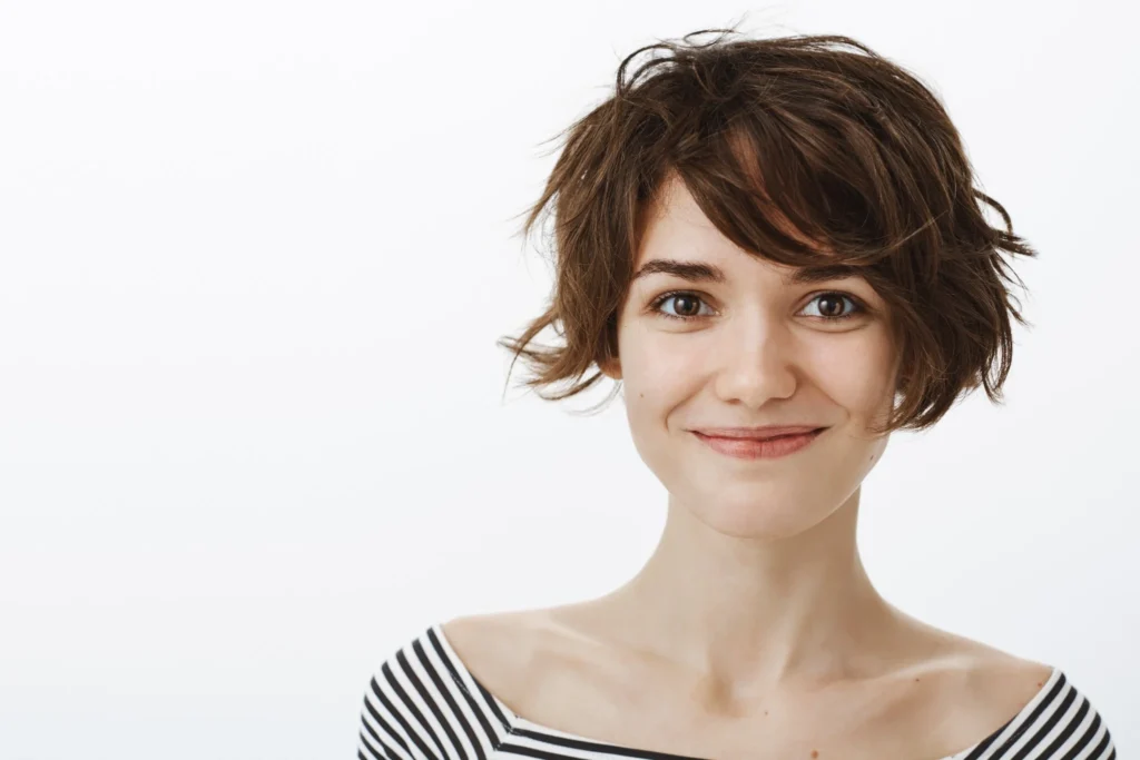 Mulher hipster sorrindo, com cabelos curtos e bagunçado, usando camiseta listrada"