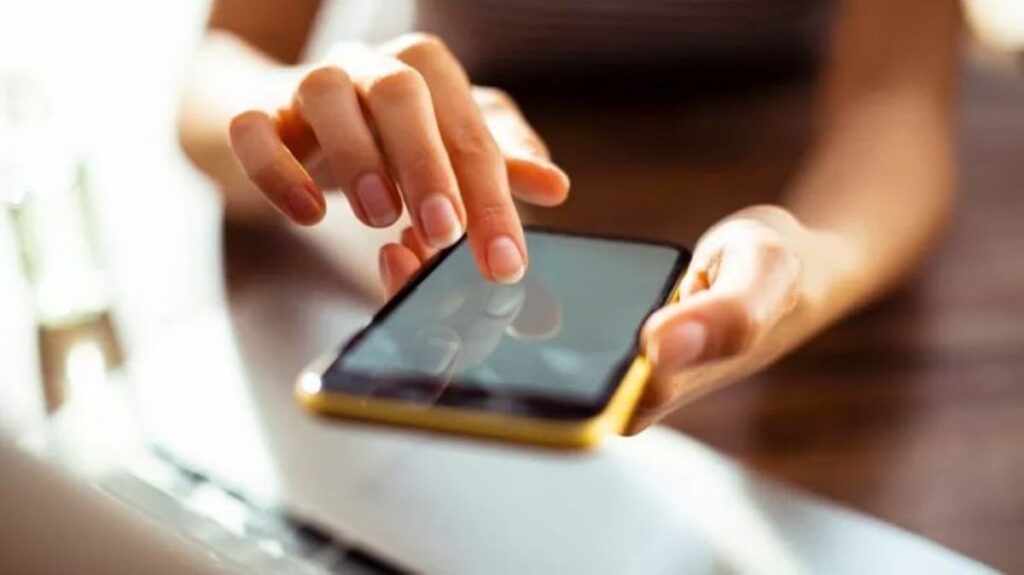 Mão feminina utilizando smartphone para gerenciamento de armazenamento e limpeza de dados
