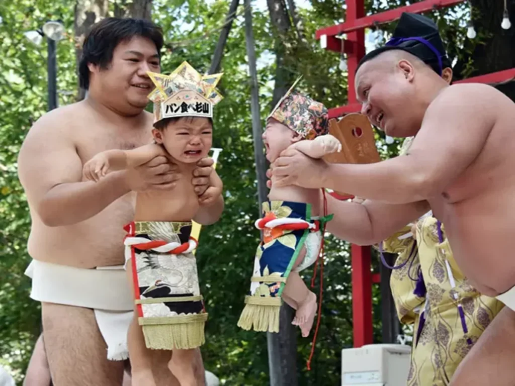 Bebês chorando durante ritual japonês tradicional segurados por homens em trajes típicos