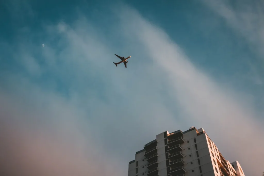Avião sobrevoando um prédio em uma tarde clara