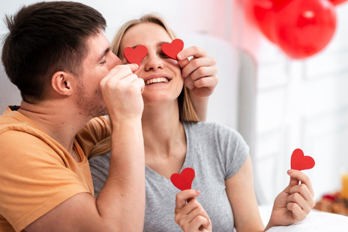 Casal brincando com corações de papel, demonstrando afeto e alegria