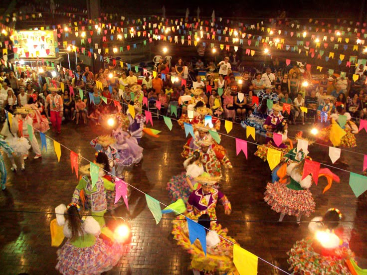 Quadrilha junina dançando em festa tradicional com bandeirinhas coloridas e público assistindo
