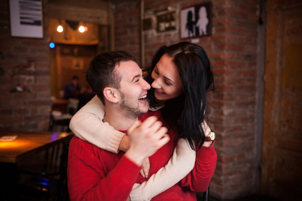 Casal sorridente se abraçando em ambiente descontraído