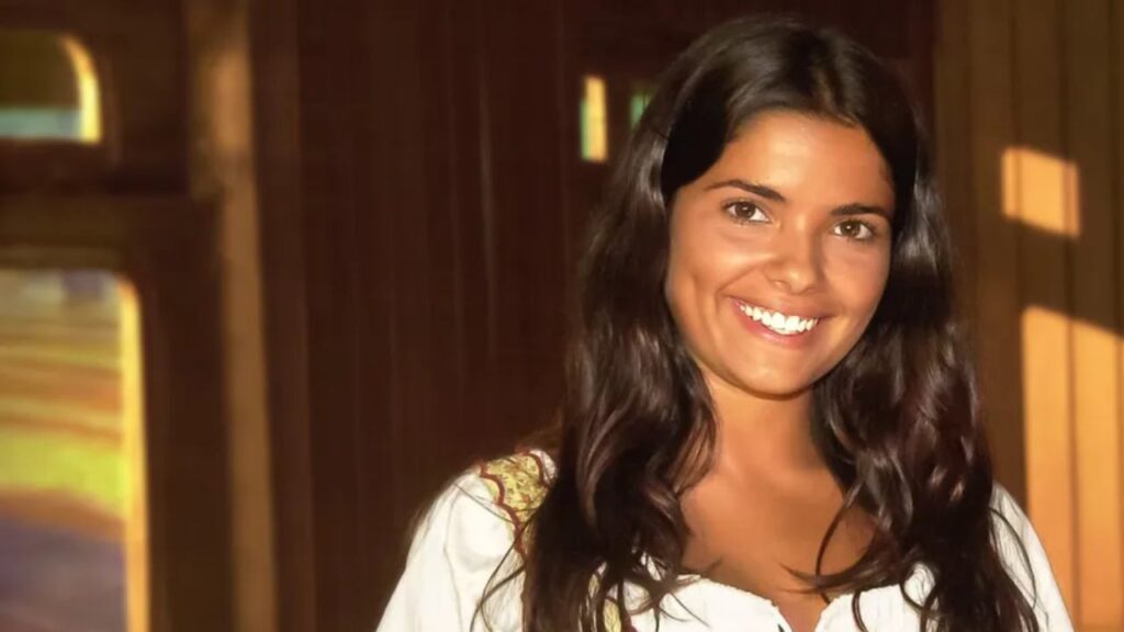 Personagem da novela Cabocla sorri em cena iluminada da trama