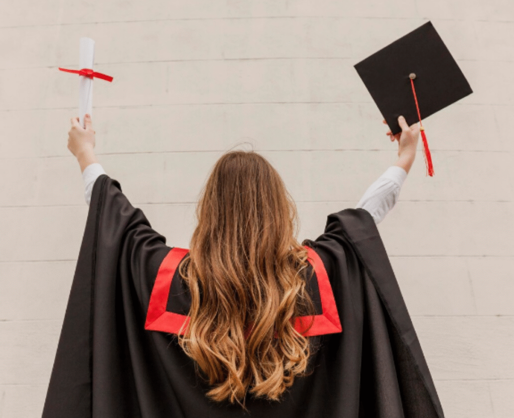 Formanda segura diploma e capelo comemorando a conclusão do curso