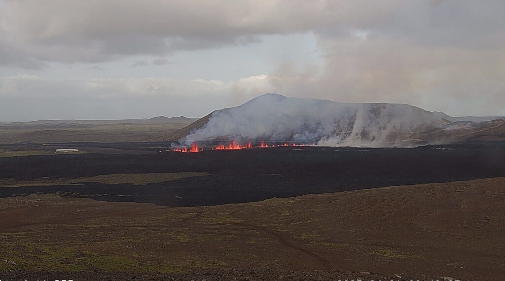 Vulcão em erupção no sudoeste da Islândia, expelindo fumaça e jatos de lava amarela e alaranjada.