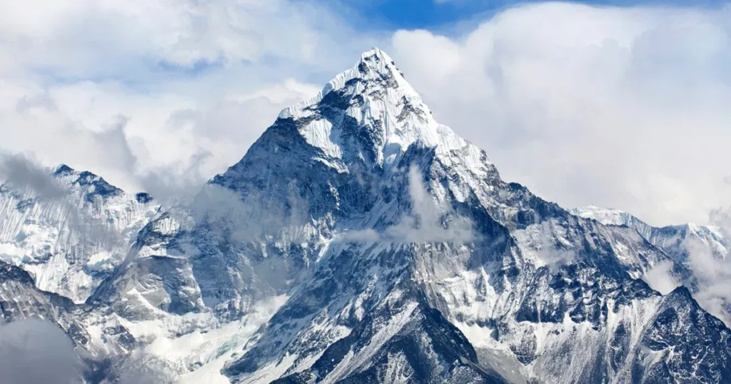 Cume nevado do Monte Everest cercado por nuvens e céu nublado