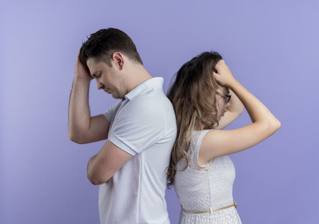 Casal em momento de tensão emocional, ambos de costas, refletindo sobre um possível término de relacionamento.