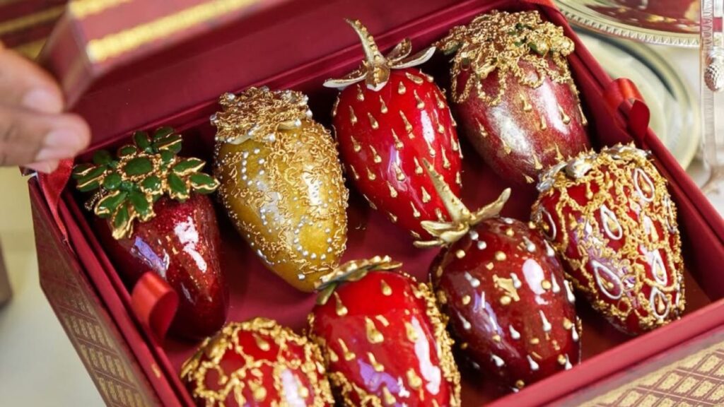 Imagem de morangos cobertos com chocolate de luxo, decorados com detalhes dourados e vendidos a preços exorbitantes, com alta demanda no mercado. Morango do amor de R$ 2.100